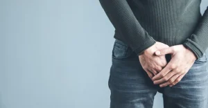 man-holding-his-urethra-pain-gray-background